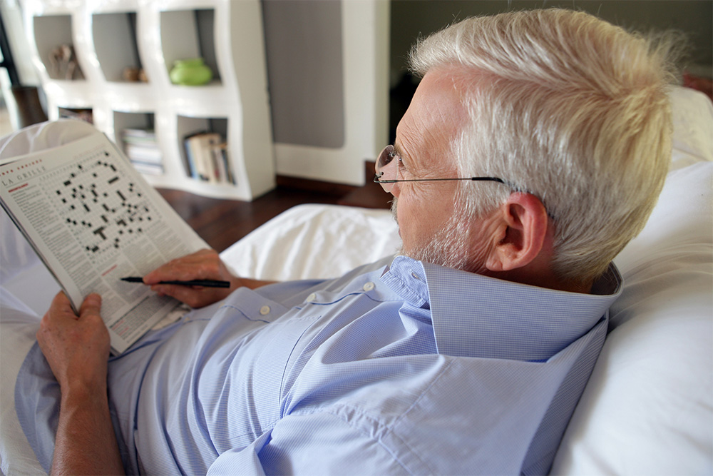 Grey-haired man completing crossword puzzle